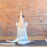 Woman sitting on a mat with her arms in front of her