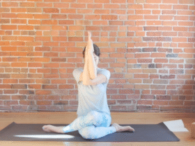 Woman sitting on a mat with her arms in front of her