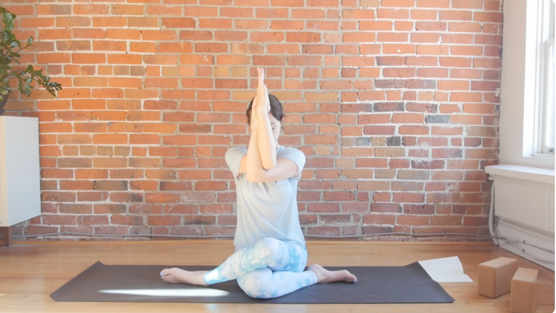 Woman sitting on a mat with her arms in front of her