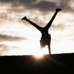 Woman turning cartwheels against a backdrop of the sunset