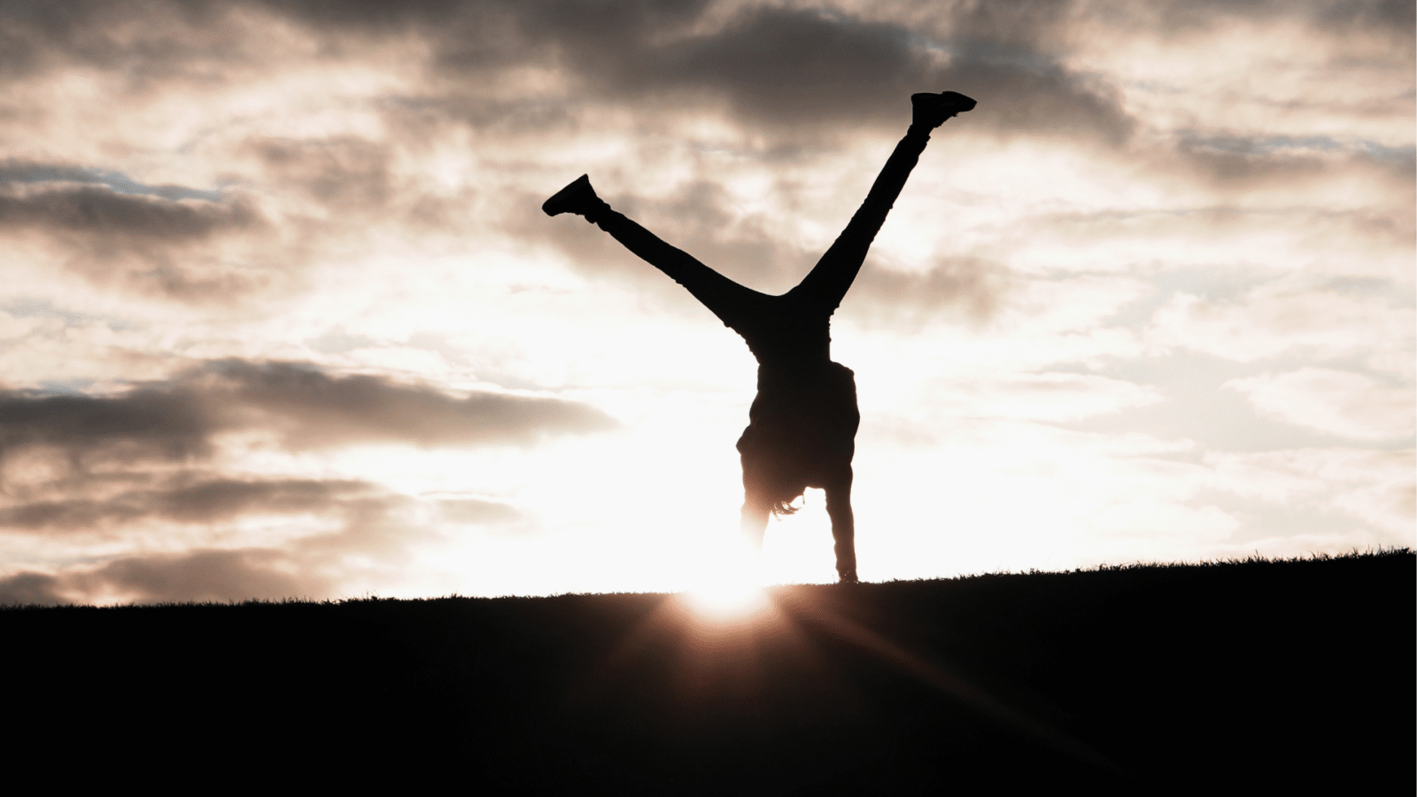 Woman turning cartwheels against a backdrop of the sunset