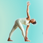Woman practicing Revolved Triangle Pose against light green background.